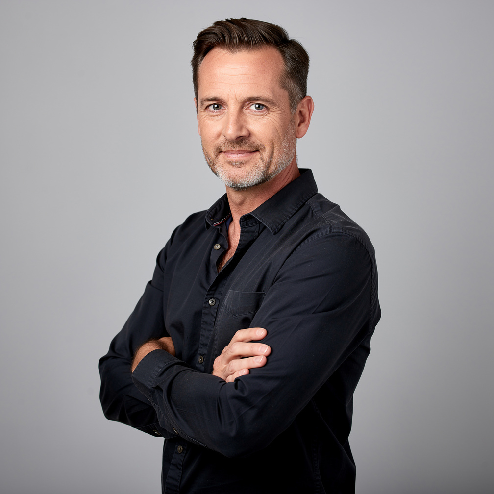 Studio portrait of a man camera operator with arms crossed